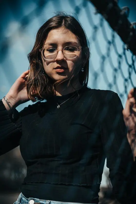 Une jeune femme avec des lunettes qui regarde vers le sol