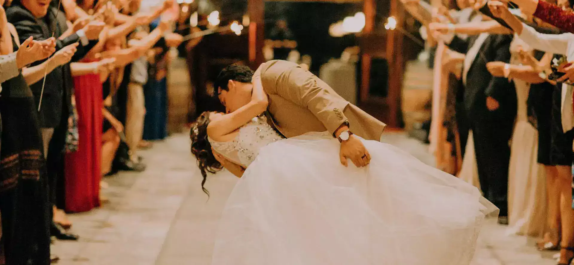 Un couple de mariés qui danse avec des gens qui applausissent autour